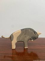 Side view of vintage wooden bull toy showing natural wood and painted gray and beige colors with a rope tail.
