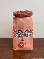 Front view of the vase showing the painted face design with eyes, red lips, and beauty mark, as well as the ruffled top