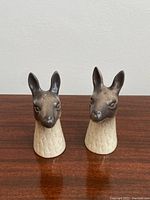 Front view of the two llama-shaped ceramic salt and pepper shakers on a wooden surface.