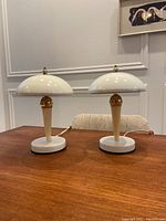 Pair of vintage mushroom style tap on lamps placed on wooden table against white wall with artwork above, showing overall condition and scale.