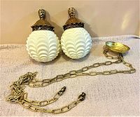 Pair of antique frosted glass globes with detailed brass fittings and long brass chains with ceiling canopy.