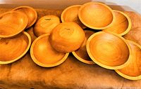 Overview of all ten wooden bowls arranged showing interior surfaces and wood grain.