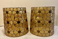 Front view of the pair of curved capiz lamp shades with floral pattern in copper framing.
