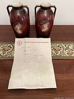 Pair of antique vases with hand-painted portraits and a certificate from Dufferin County Museum and Archives dated circa 1910-1920.