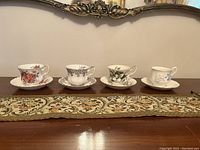 Four porcelain cups and saucers displayed side by side showing different floral designs