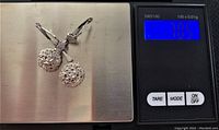 Pair of earrings on scale showing total weight of 7.05g