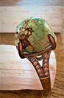 Close-up image capturing the turquoise stone and detail on the silver ring band with accent stones.