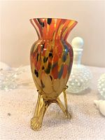 Photo showing the full Murano glass vase with multicolor spotted design and golden tripod base on a cloth surface