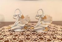 Pair of vintage Capodimonte porcelain ballerina figurines shown on lace tablecloth with clear details of gold trim and sculpted skirts.
