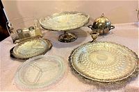 Full set overview showing all the serving pieces arranged on a table including trays, glass dishes, shakers, candlestick holder, and covered dish.