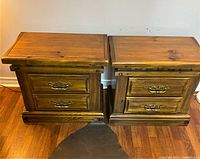 Pair of vintage bedside drawers captured from the front, showing their medium brown wood finish and brass handles.