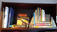 Books on a wooden shelf held upright by two triangular onyx bookends with green and cream colors.