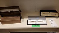 Three Cross pens with original boxes displayed on a table, showing different pen styles and their boxes.