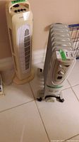 View of Airworks tower heater and classic oil-filled radiator fan heater side by side on tile floor