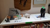 Overview of all soapstone sculptures, whale art slab, bone carving and print on table