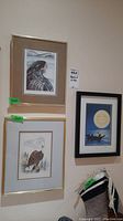 Three framed Indigenous prints hanging on a wall; two eagle prints and one canoe scene print.