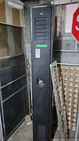 Front view of black metal locker with ventilation slats and number 13 on top center door area, includes combination lock at mid-height.