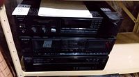 Full view of the Sony stereo system setup on shelves showing three main components stacked, with user manual and remote on top.