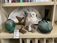 Lot displayed on shelf showing the statues, vases, fan, and bowl as a whole.