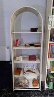 Full view of wicker shelf with five shelves, showing shape and stored contents
