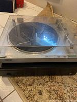Sony PS-LX3 turntable with clear dust cover showing visible crack placed on top of a black Niles amplifier.