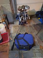 Photo showing golf clubs in blue Nike stand bag with extended legs, clubs including irons and woods visible.