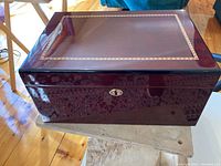 Front view showing the dark reddish wood finish, glossy surface, and metal locking clasp.
