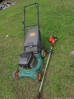 Side angle showing green Weed Eater lawnmower with black engine cover, yellow wheels, and rear black fabric bag on grass along with red Homelite Mighty Lite 26SS edger lying beside it.