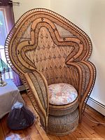 Front view of vintage wicker peacock cobra chair with floral cushion