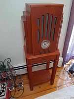 Full view of the Crosley CR18CD unit on a wooden stand, showing the rectangular wooden cabinet with side wings and front speaker grills with metal mesh