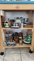 Wide shelf view showing various kitchen items including candle holders, ice bucket, teapot, cutting boards, coasters, and pitchers