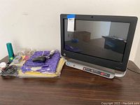 View of HP TouchSmart PC with power and data cables, mouse, and office items on table