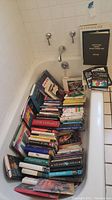 Photo of large stack of nonfiction books in a bathtub