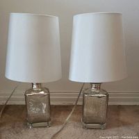 Pair of glass lamps side by side showing textured clear glass bases and white shades.