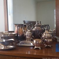 Group photo showing entire W M Rogers silverplate serving set with teapot, pitcher, sugar bowl, creamer, butter dish, and gravy items on wooden table.