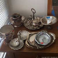Full view of assorted silverplate serving items including platters, bowls, and covered sugar and creamer set