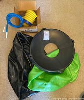 Photo showing deflated green yoga balls, black plastic base, and cardboard box with yellow and blue pumps inside