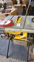 Full front view of DeWalt table saw mounted on folding supports showing cast metal top, height/angle adjustment wheels, and installed blade