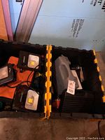Two plastic tool boxes containing LED work lights, rubber straps, and Ridgid drill