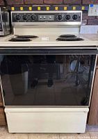 Front view of Kenmore electric stove showing four coil burners and oven door with glossy black finish.