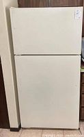 Front view of the white Maytag refrigerator freezer unit with closed doors, showing clean flat panels and handle indentations.