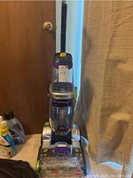 Front view of Bissell Revolution Pet Pro Carpet Cleaner upright unit on carpet, next to door and curtain.
