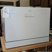 Front view of the white SPT mini dishwasher, showing clean exterior with minor scratches and a center handle.