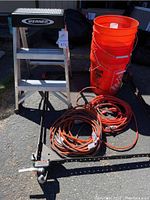 Photo of Werner step stool, orange buckets, extension cords, and metal frame with wheels arranged outdoors