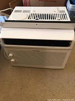 Front view of Toshiba air conditioner showing control knobs and vent grille.