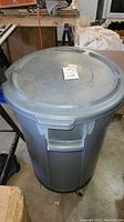 Full view of one grey plastic trash can with lid and side handles