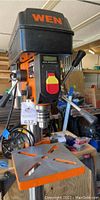 Front view of drill press head showing WEN branding, speed control lever, and cast iron work table with slotted top.