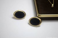 Pair of oval black onyx earrings with twisted rope gold border on white background