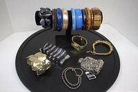 Lot of bracelets displayed on a black round display with various styles and materials including metal, plastic and elastic.