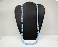 Full view of the long necklace displayed on a black stand.